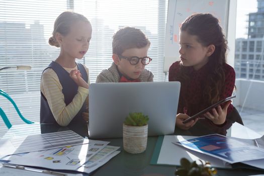 Business people discussing over technology at table in office