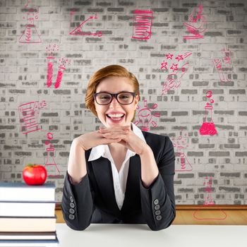 Redhead teacher sitting at desk against red apple on pile of books