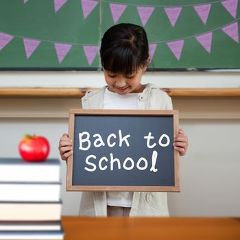 Back to school message against cute pupil showing chalkboard