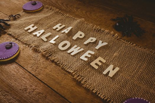 High angle view of happy Halloween text on sack with decorations at wooden table