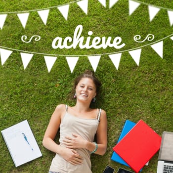 The word achieve and bunting against pretty student lying on grass