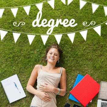 The word degree and bunting against pretty student lying on grass