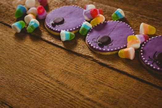 Close up of Halloween cookies with candies on wooden table