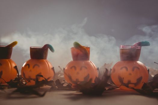 Food in jack o lantern containers with autumn leaves on table during Halloween