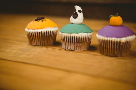 Close up of colorful cup cakes on wooden table during Halloween