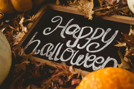 High angle view of happy halloween text on slate amidst autumn leaves