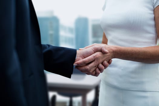 Digital composite of Business people shaking hands against office background