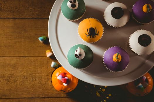 Overhead view of cup cakes with decorations on wooden table during Halloween