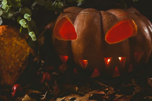 Close up of jack o lantern with autumn leaves on table during Halloween