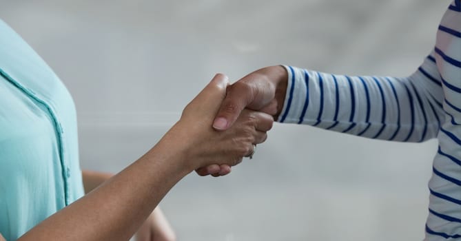 Digital composite of Business people shaking hands against grey background