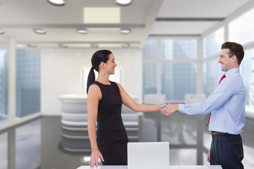 Digital composite of Happy business people shaking hands against office background