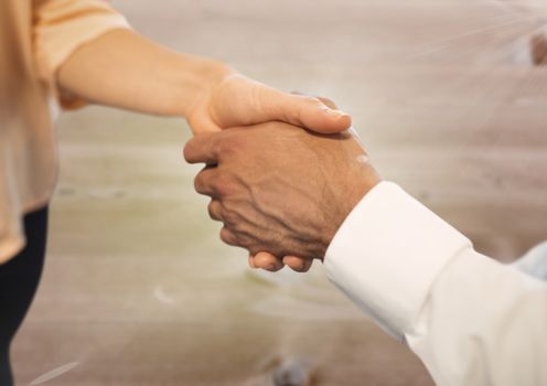 Digital composite of Business people shaking hands against wood floor background