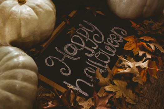 High angle view of happy Halloween text on slate with pumpkins and autumn leaves