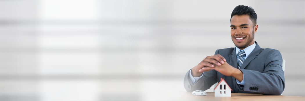 Digital composite of Man standing behind a table with a house and a car as house and car insurance concept