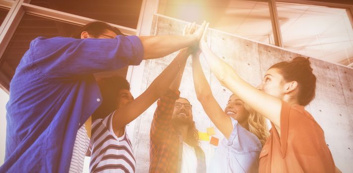 Low angle view of cheerful business people giving high five in creative office