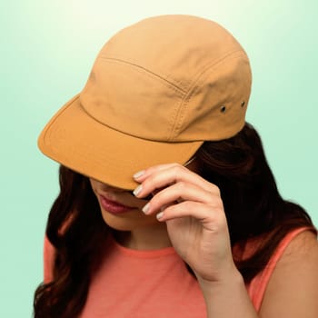 Woman with long hair wearing brown cap against blue background