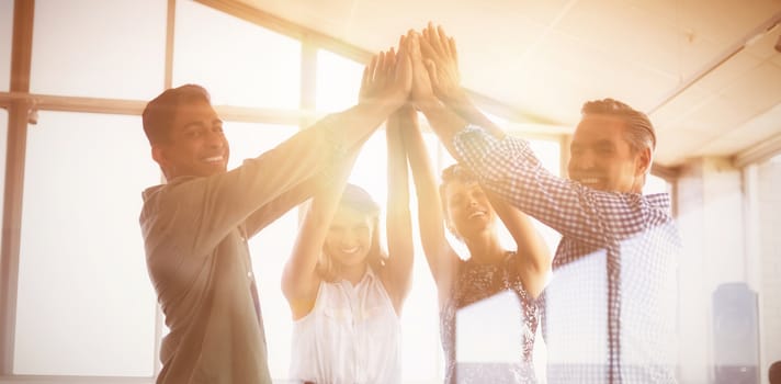 Portrait of business people raising hands seen through glass at creative office