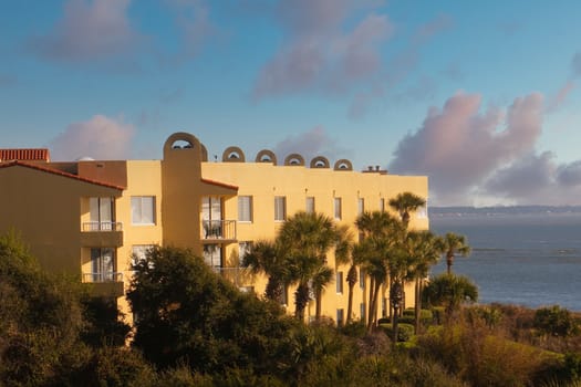 A yellow stucco seaside hotel with palm trees