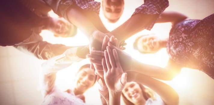 Directly below portrait of smiling business people stacking hands together at creative office