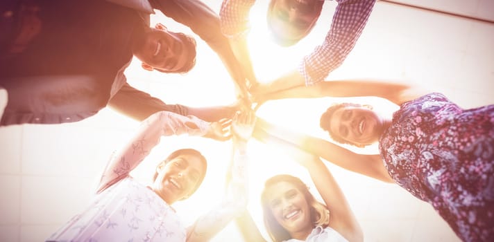 Directly below portrait of smiling business people raising hands at creative office