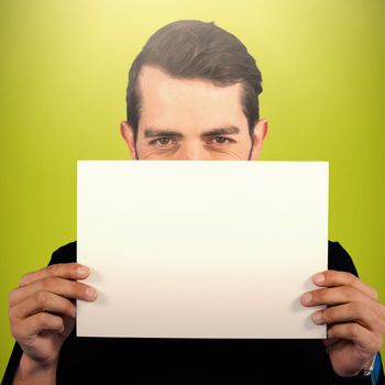 Portrait of young man hiding face with cardboard against green background