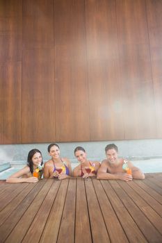 Portrait of cheerful young people with drinks in the swimming pool