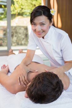 Portrait of a female masseur massaging mans back at spa center