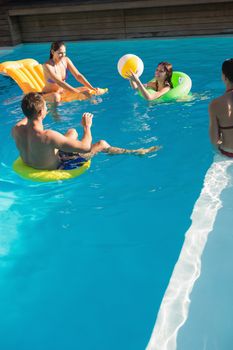 Cheerful young people playing with ball in swimming pool