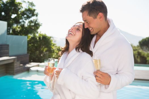 Cheerful romantic young couple with champagne flutes by swimming pool