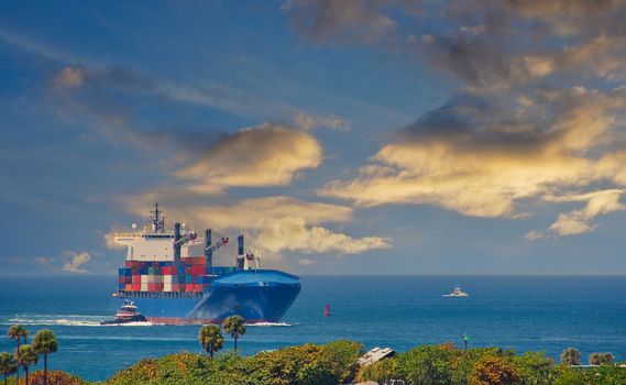 A loaded freighter being guided into a port with a tugboat