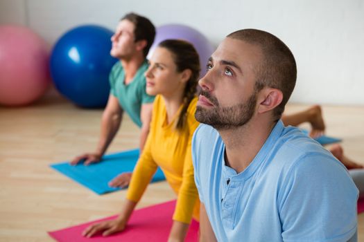 Yoga instructor guiding students in practicing cobra pose at health club