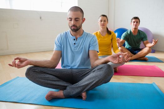 Yoga instructor with students meditating at health club 