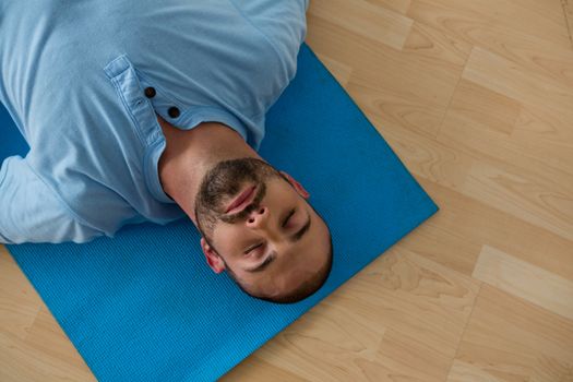 High angle view of yoga instructor exercising while lying on mat in yoga studio