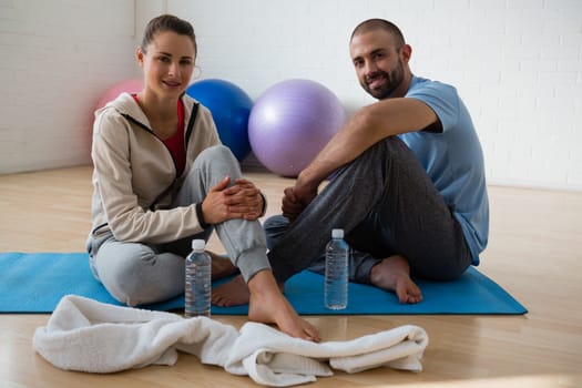 Portrait of female student with instructor relaxing in yoga studio