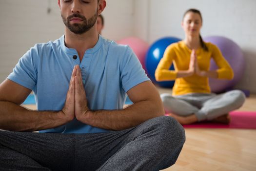 Yoga instructor with student meditating in prayer position at health club 