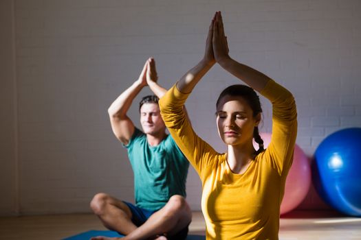 People meditating in prayer position at health club