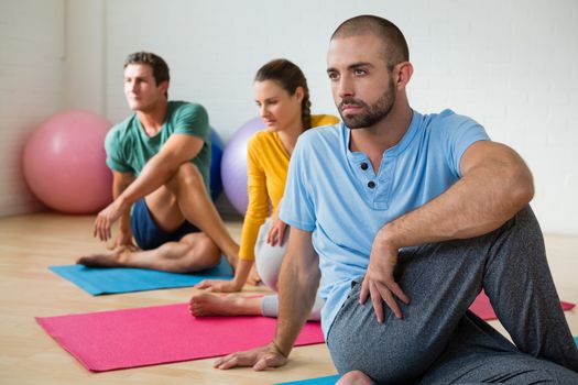 Yoga instructor guiding students in practicing Ardha Matsyendrasana at health club
