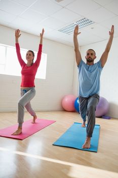 Yoga instructor with student practicing warrior 1 pose in health club