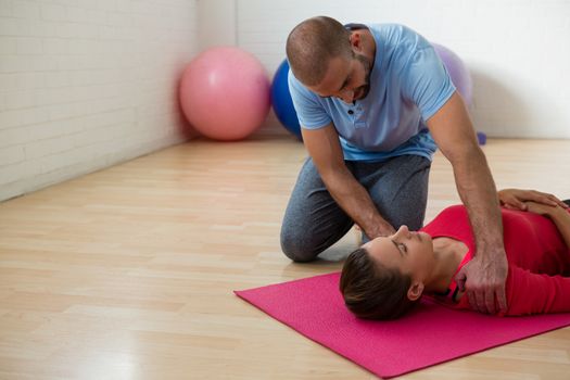 Yoga instructor guiding student in exercising at health club