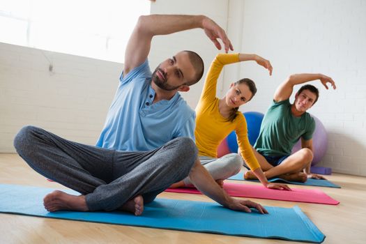Male instructor with students exercising at yoga studio