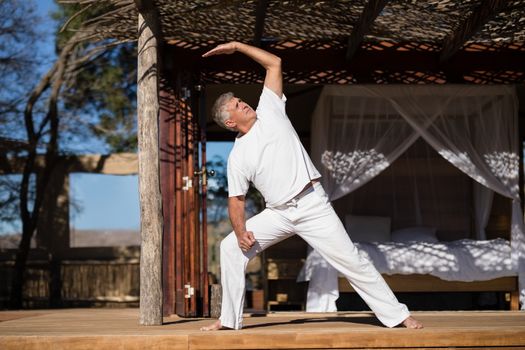 Man practicing yoga in cottage on a sunny day