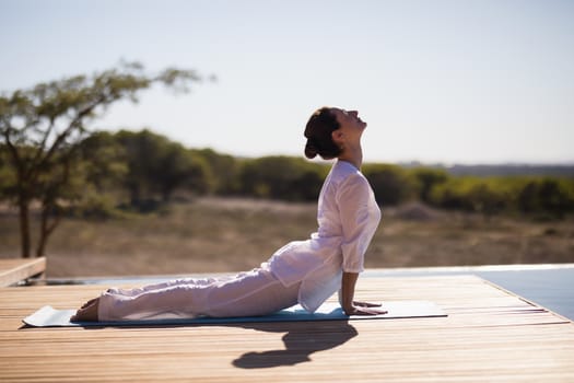 Woman practicing yoga on at poolside on a sunny day