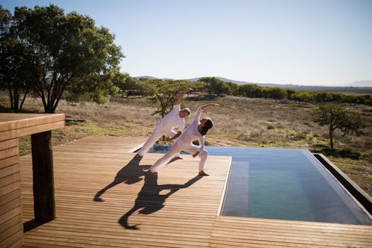 Couple practicing yoga on wooden plank on a sunny day