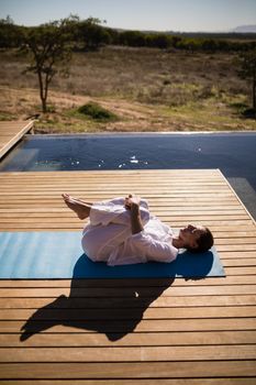 Woman practicing yoga on at poolside on a sunny day