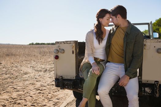 Young romantic couple sitting in off road vehicle at landscape