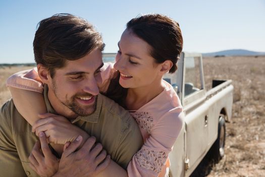 Romantic young couple by parked off road vehicle on landscape
