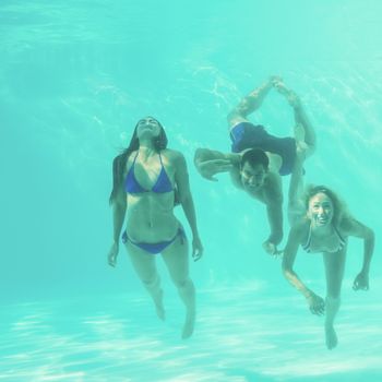 Group of young friends underwater in swimming pool
