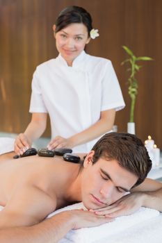 Close up of a handsome young man receiving stone massage at spa center