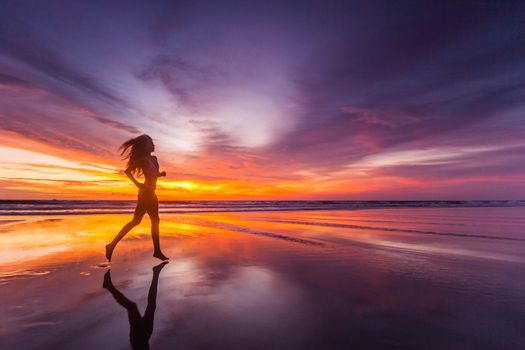 Picture of sexy female running on the beach, in a stylish bikini enjoying summer vacation at sunset copy space background