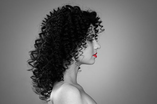 Profile portrait of young caucasian woman with curly hair and red lips